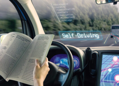 Interior of a self driving car with a smart dashboard and windshield while person reads a book