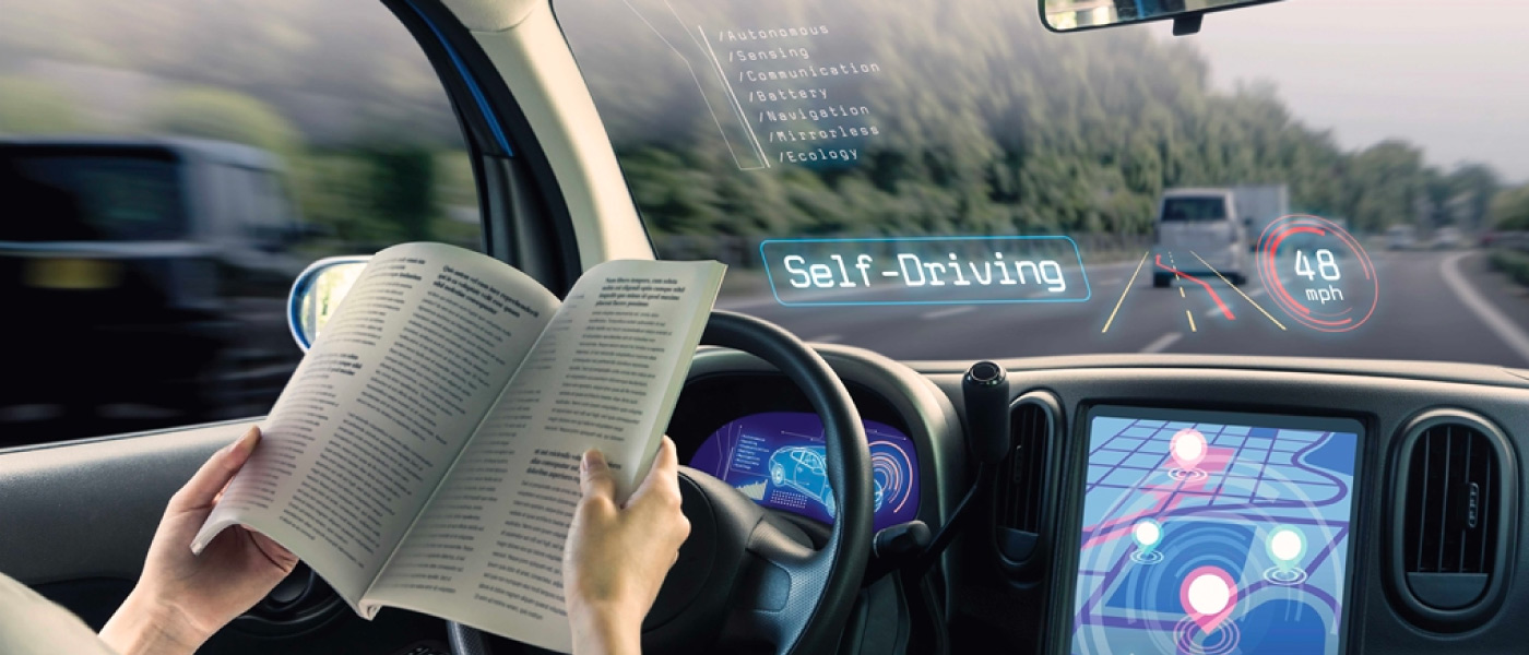 Interior of a self driving car with a smart dashboard and windshield while person reads a book