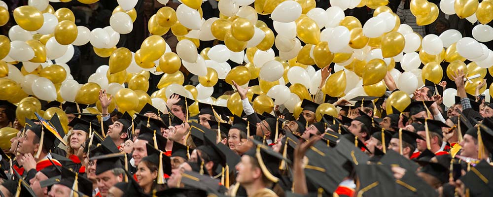A graduation ceremony at Georgia tech with graduates and white and gold balloons